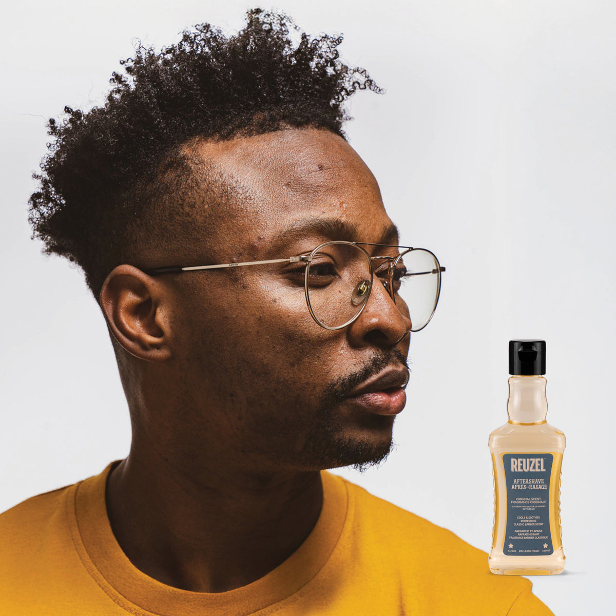 Reuzel UK beard aftershave in a glass bottle with a black cap, featuring the Reuzel logo on the label.