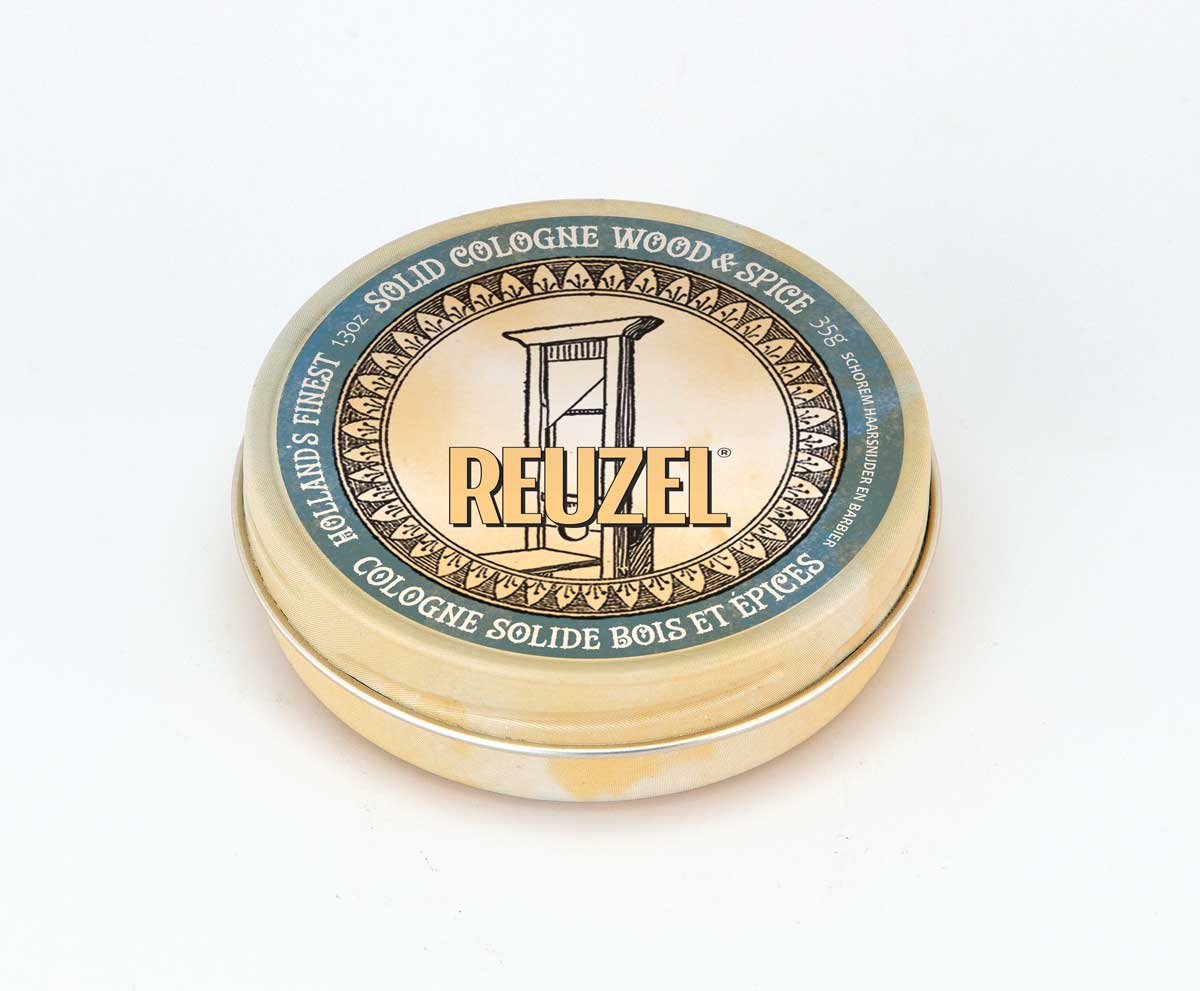 Wood and spice solid cologne balm by REUZEL UK, showing a tin container with the balm inside and a wooden surface background.