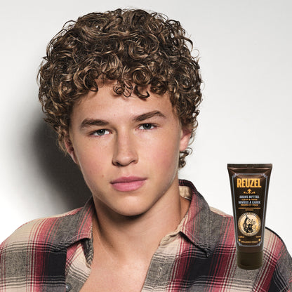 Person with styled hair next to a bottle of Reuzel product on a plain background