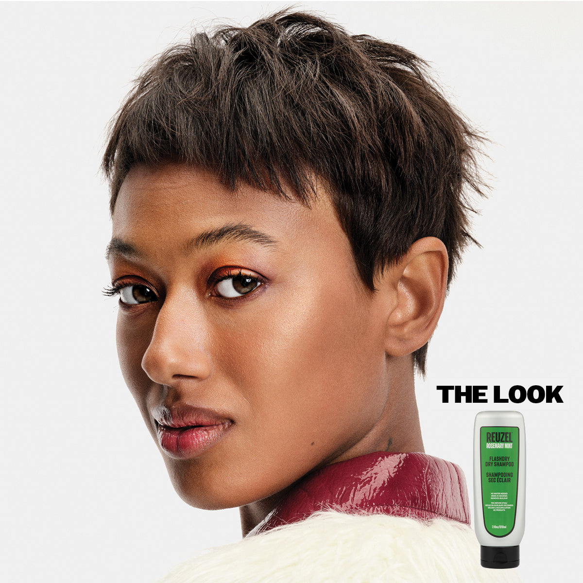 Woman with styled hair and a bottle Reuzel Flashdry Shampoo.