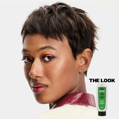 Woman with styled hair and a bottle Reuzel Flashdry Shampoo.