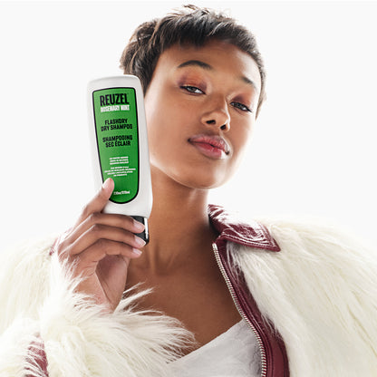 Woman holding a Reuzel dry shampoo bottle against a white background