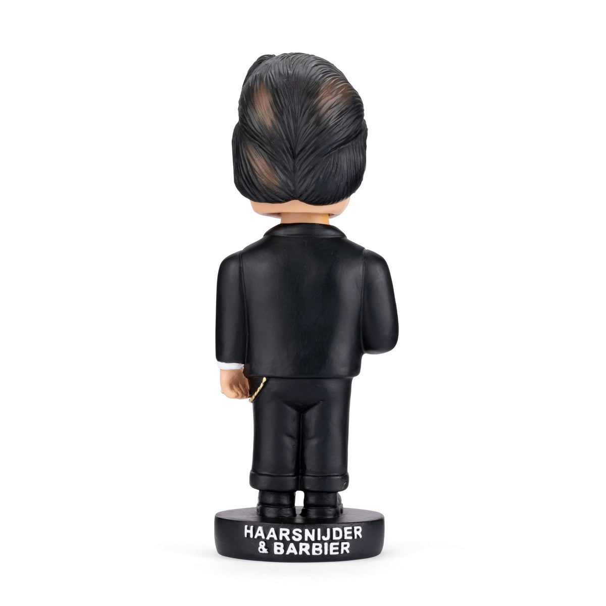 A bobblehead figurine shown from the back, wearing a black suit and standing on a black base labeled 'HAARSNIJDIER & BARBIER'. The figure has dark hair with lighter streaks and a small gold chain detail.